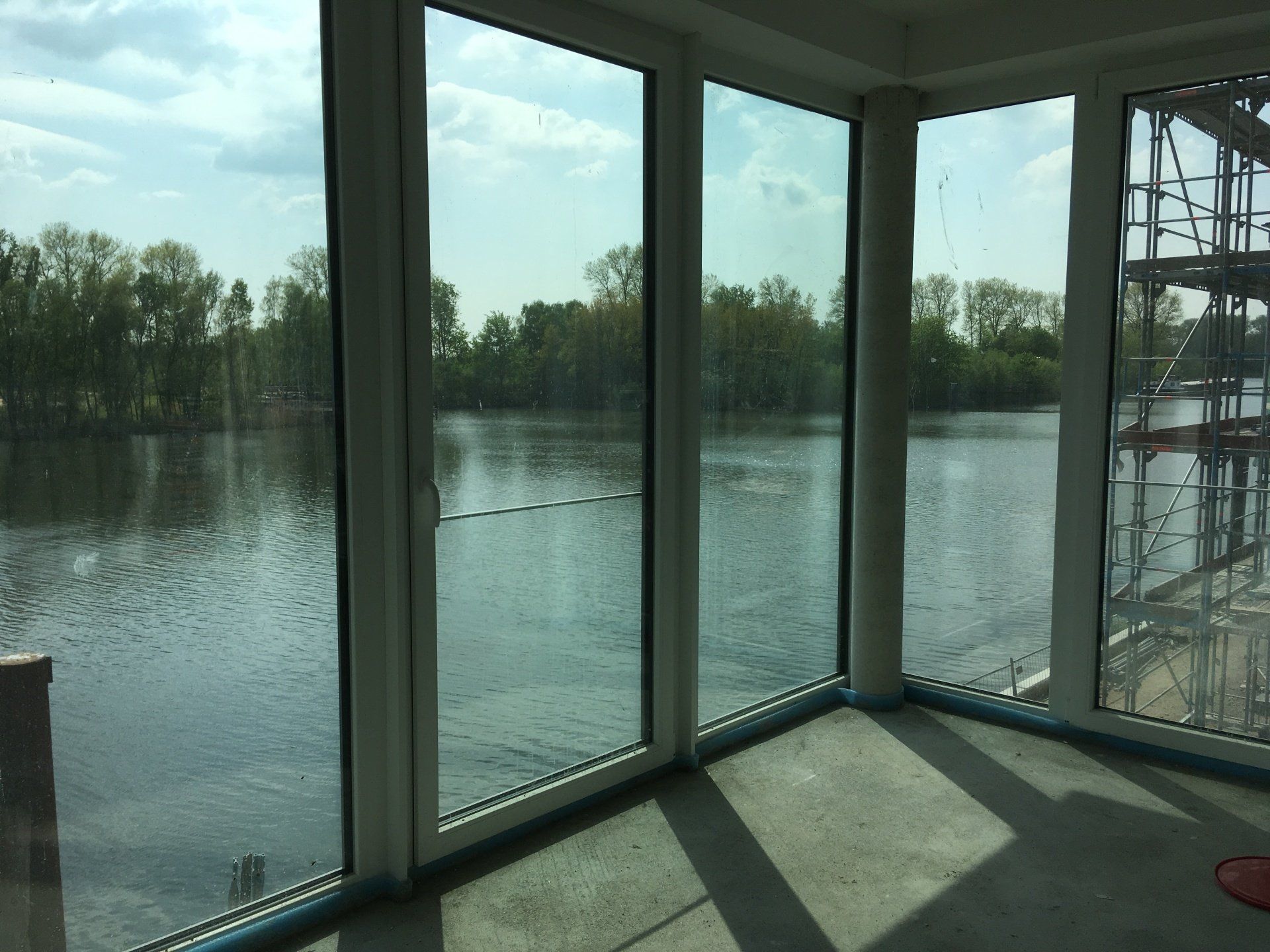 Sonnendurchfluteter Innenbereich mit Blick durch große Fenster auf einen ruhigen Fluss und Bäume draußen