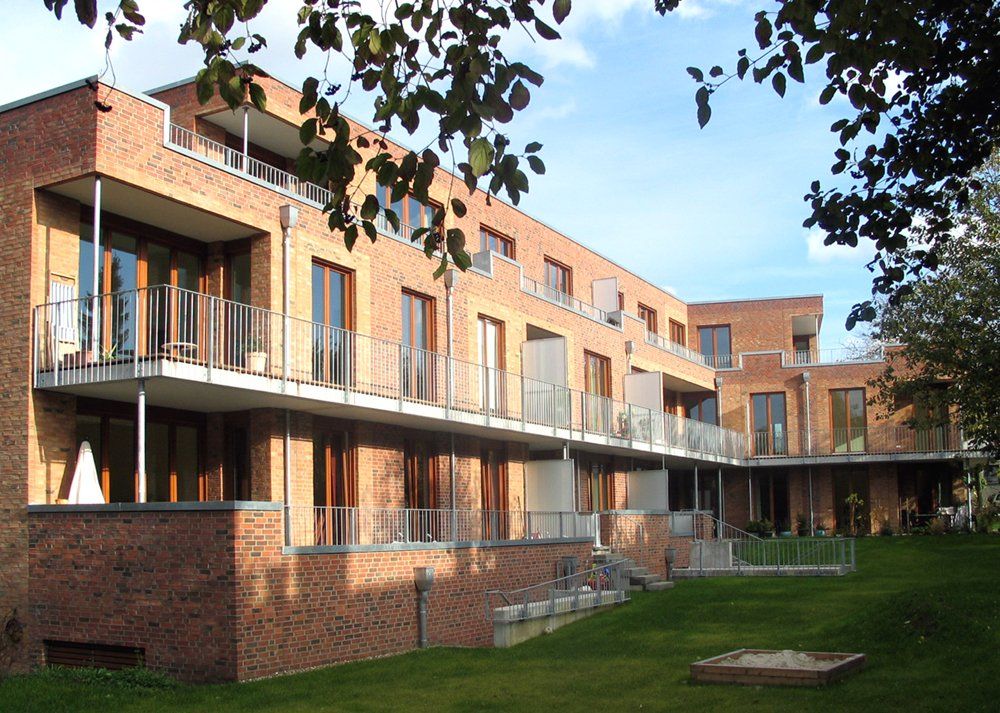 Modernes Backstein-Mehrfamilienhaus mit Balkonen und einem begrünten Innenhof
