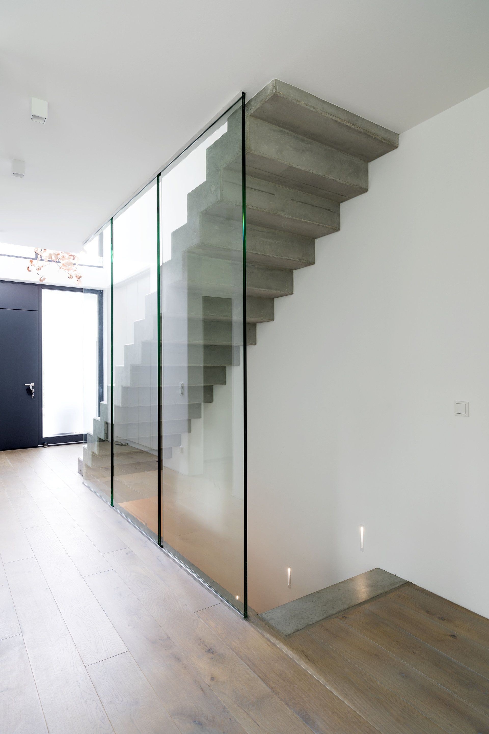 Moderne Innentreppe mit Glasgeländer in einem hellen Flur