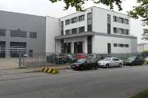 Modernes weißes Bürogebäude mit parkenden Autos entlang der Straße