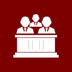 A group of men are sitting at a table in a courtroom.
