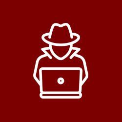 A man in a hat is sitting in front of a laptop computer.