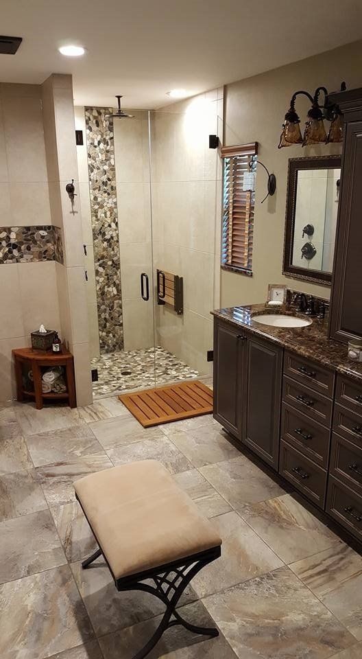 Bathroom with a walk-in shower, vanity, wooden floors, and a bench. Earth-toned colors dominate.