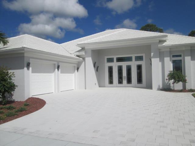 White stucco house with white driveway, garage, and entry door, against a blue sky.
