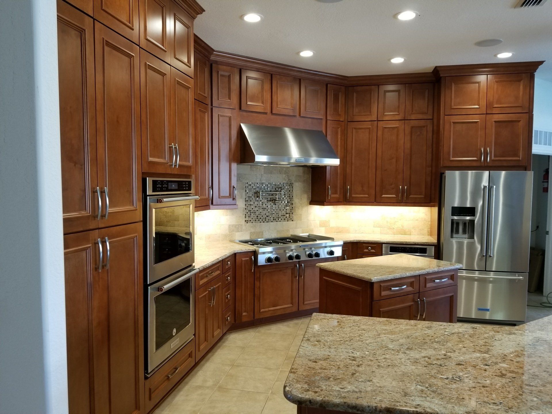 Kitchen with cherry cabinets, stainless steel appliances, granite countertops, and an island.