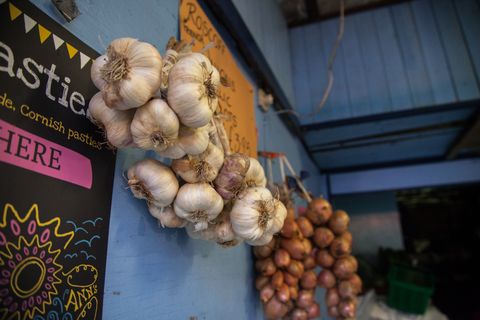 Fresh garlic and onions hung in the sheltered part of the stall. Perran-ar-Worthal, Cornwall. 30.10.15. Fresh garlic and onions hung in the sheltered part of the stall. Perran-ar-Worthal, Cornwall. 30.10.15.