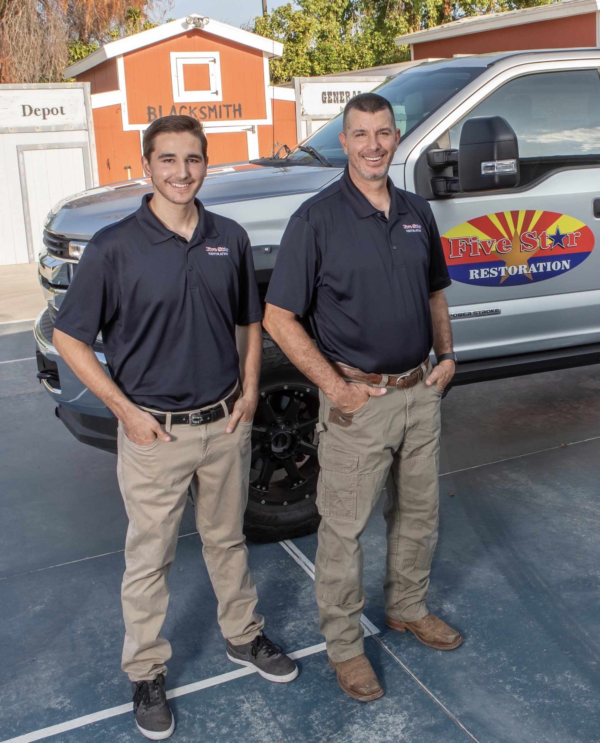 Two men are standing next to a truck in a parking lot.