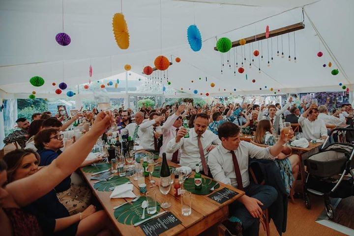 A large group of people are sitting at tables in a tent.