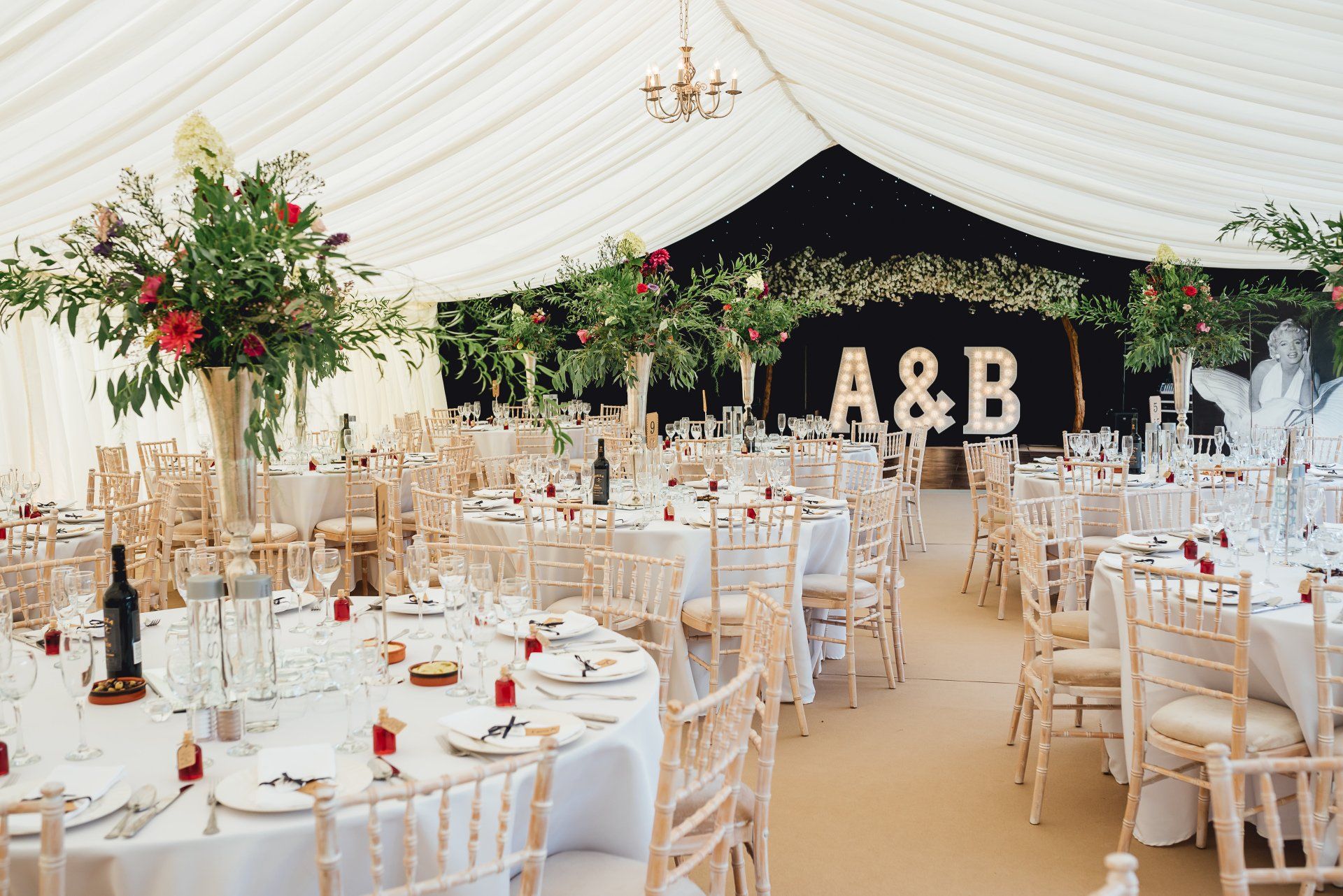 A large tent with tables and chairs set up for a wedding reception.