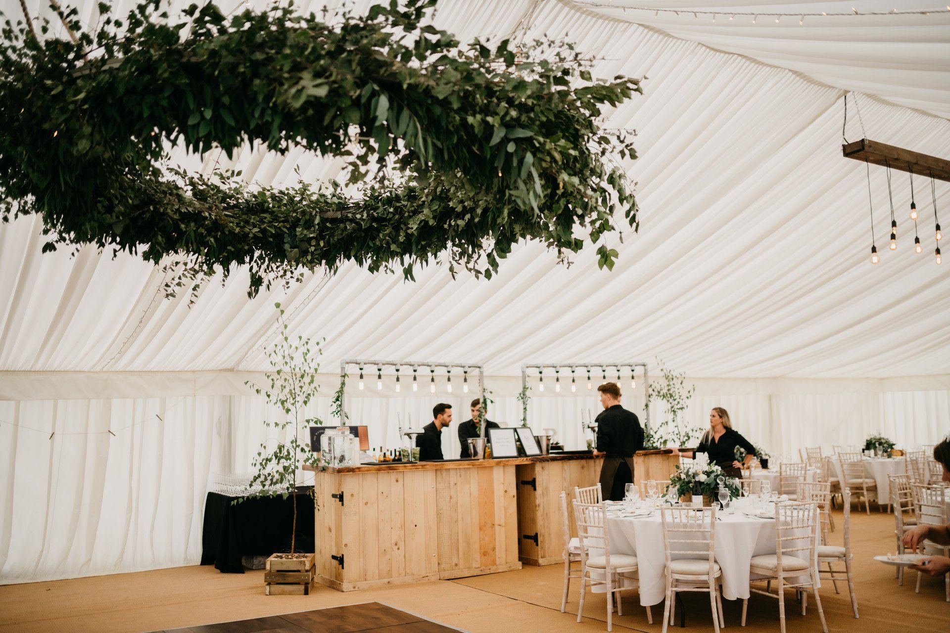 A tent with tables and chairs and a wreath hanging from the ceiling.