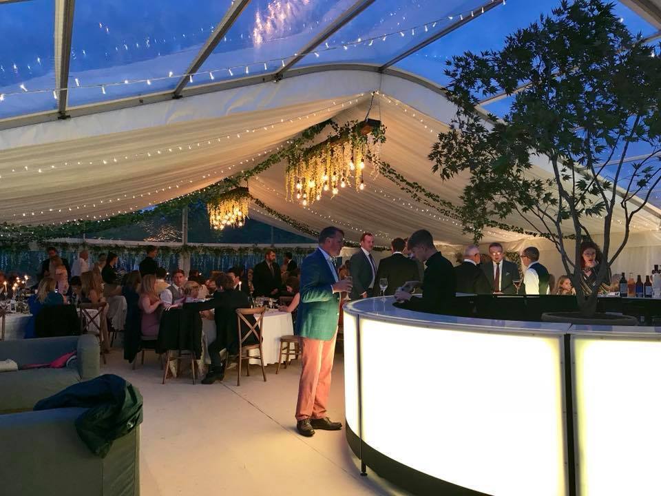 A group of people are sitting at tables under a clear tent.