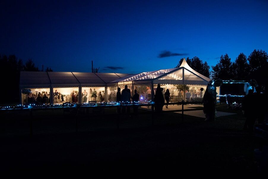 A large tent is lit up at night with people standing in front of it.