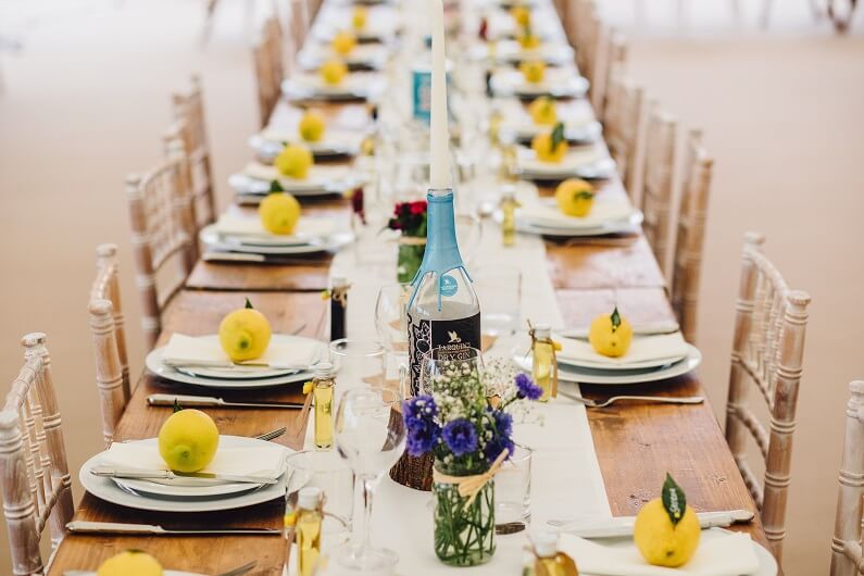 A long wooden table set for a wedding breakfast within a marquee in Worcestershire