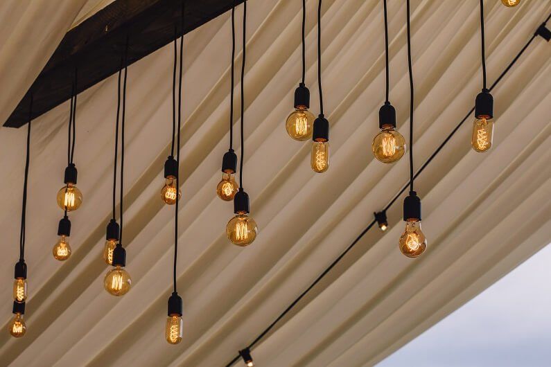 Hanging lights light a ceiling within a marquee for a wedding in Worcestershire