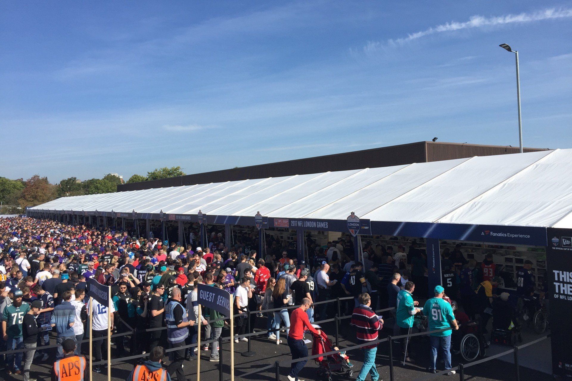 A large crowd of people are gathered under a white tent.