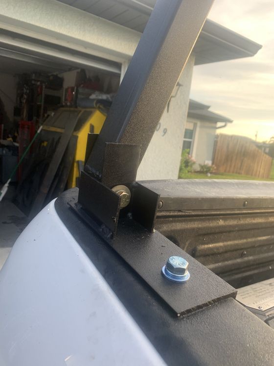 Black metal truck rack bolted to a white truck bed.