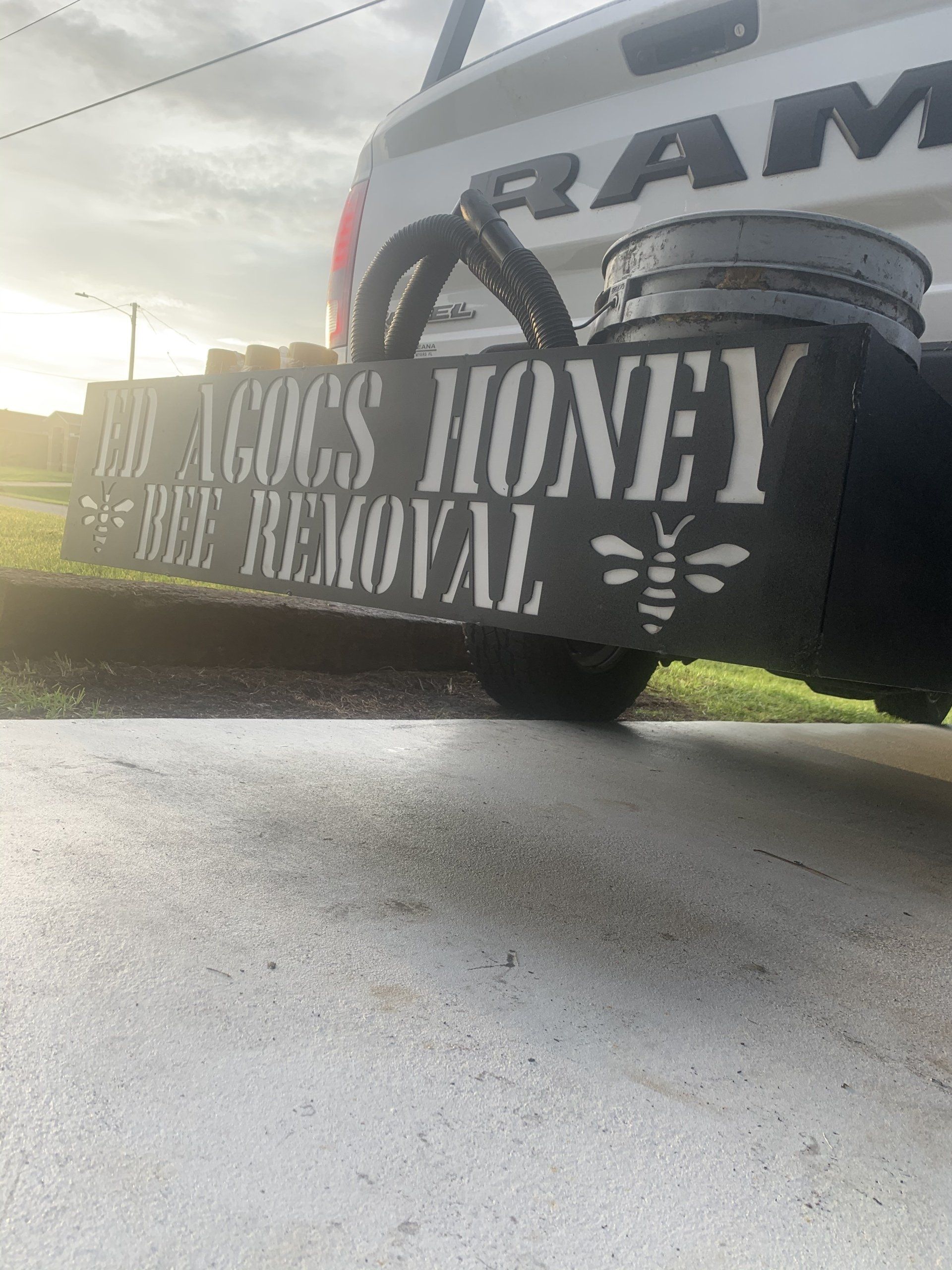 Black sign attached to a white truck bumper: 