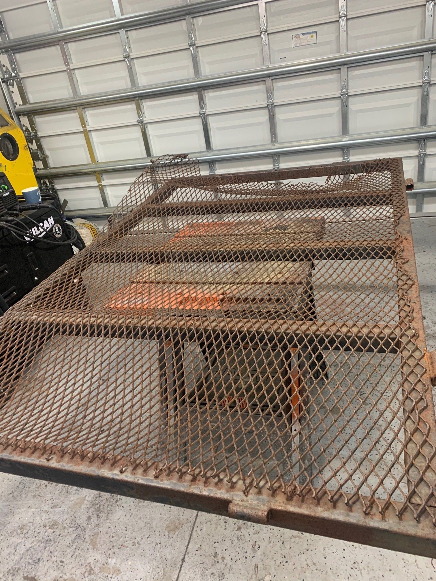 A rusted metal cage, likely for a trailer bed, with a metal mesh exterior and wood supports inside.