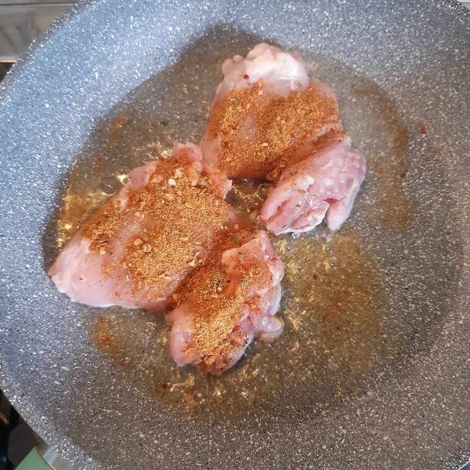 Kipstukjes gekruid met specerijen, gebakken in een grijze koekenpan in olie.