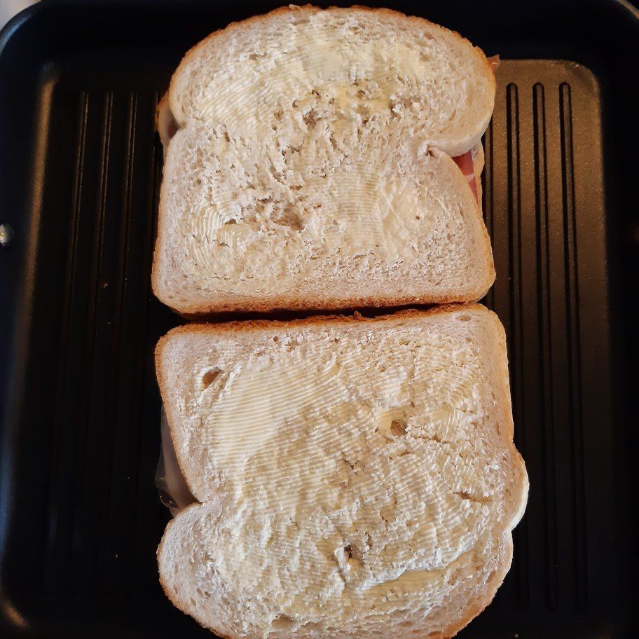 Een sandwich met beboterd brood, gebakken in een grillpan.