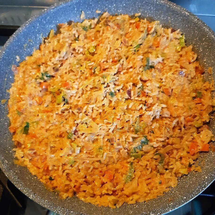 Een pan gekookte rijst met groenten, oranje van kleur.
