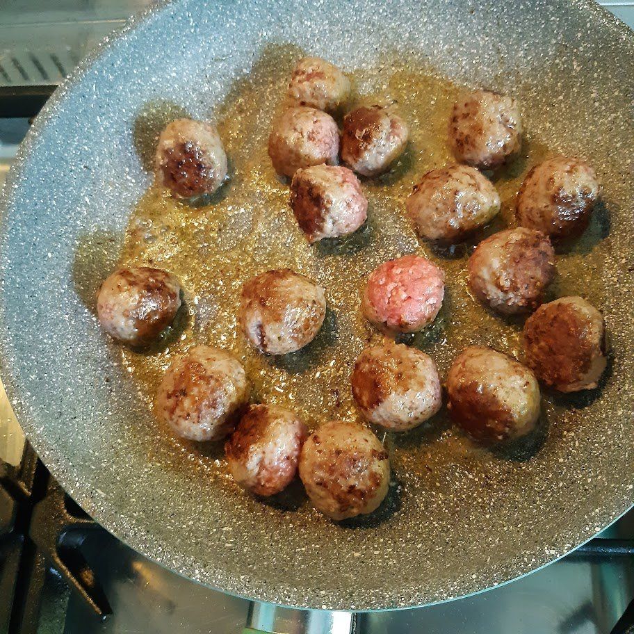 Gehaktballetjes bakken in een pan met olie op het fornuis.