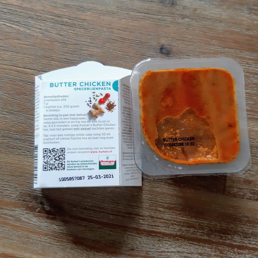 Kant-en-klaarmaaltijd met boterkip voor in de magnetron; open de verpakking op een houten ondergrond.