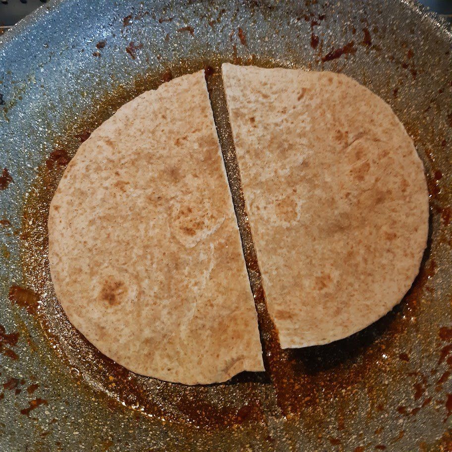 Een doormidden gesneden platbrood in een pan bakken.