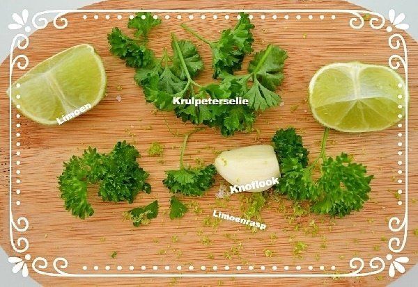 Limoenen, peterselie, knoflook en limoenschil op een houten snijplank.