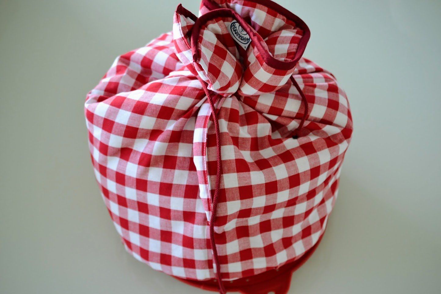 Een bundel rood-wit geblokte stof, dichtgebonden, mogelijk om spullen in te vervoeren.
