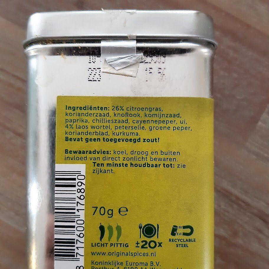 Close-up van het achteretiket van een kruidenblikje. De tekst vermeldt de ingrediënten (citronella, koriander, enz.), het gewicht en de houdbaarheidsdatum.