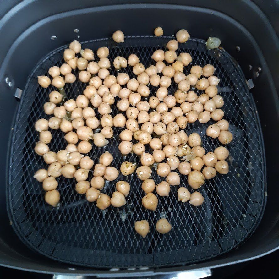 Airfryer met kikkererwten op een zwart rooster.