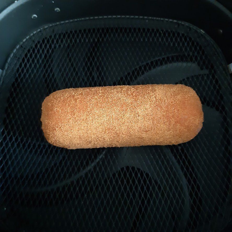 Gepaneerd voedselproduct in een zwarte airfryer.