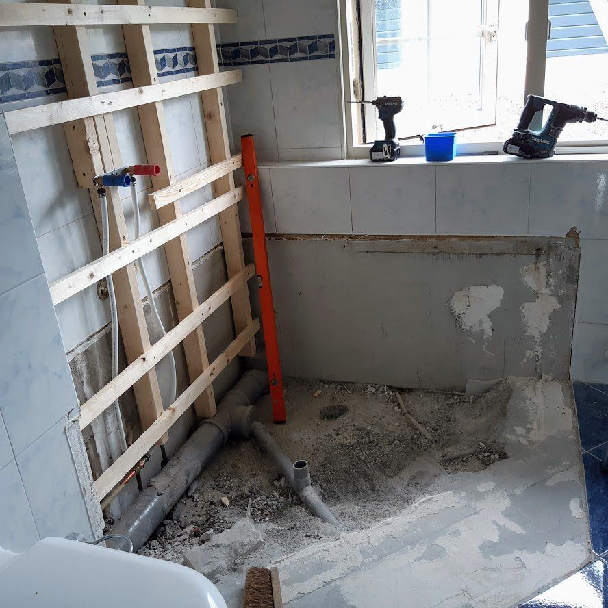 Badkamer in renovatie, met een houten frame, leidingen en gereedschap.