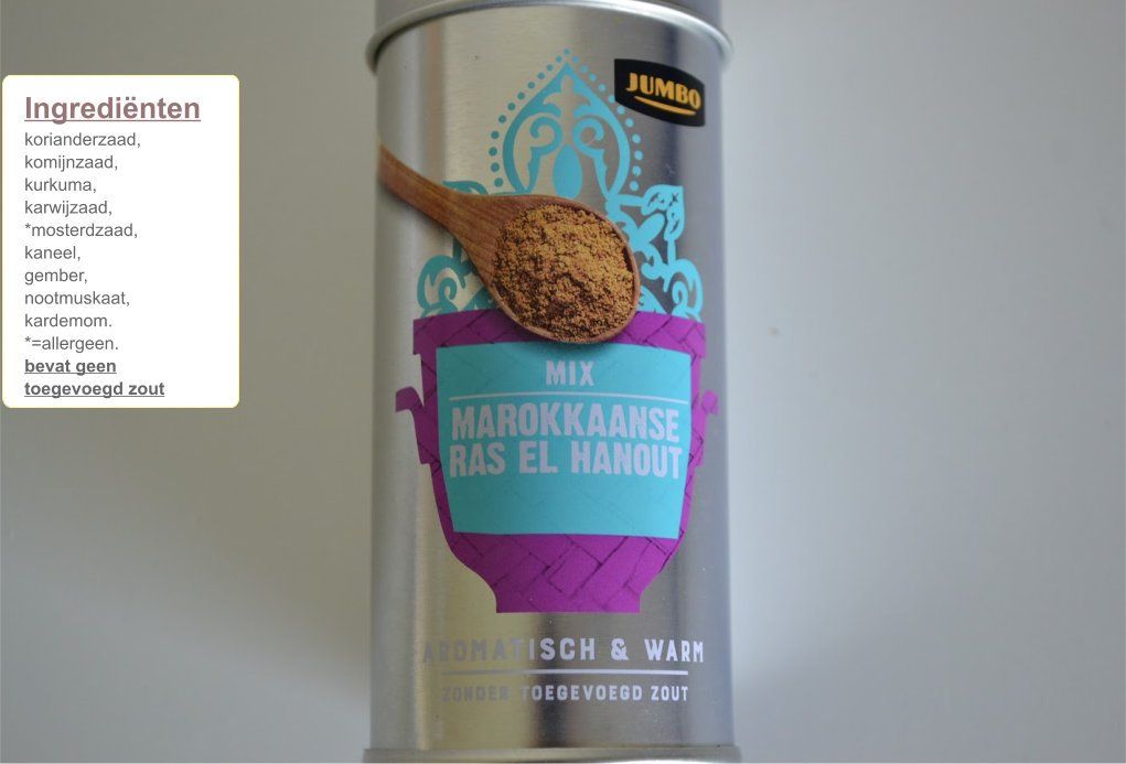 Een grote blik Marokkaanse Ras el Hanout kruidenmix met een houten lepel en een ingrediëntenlijst.