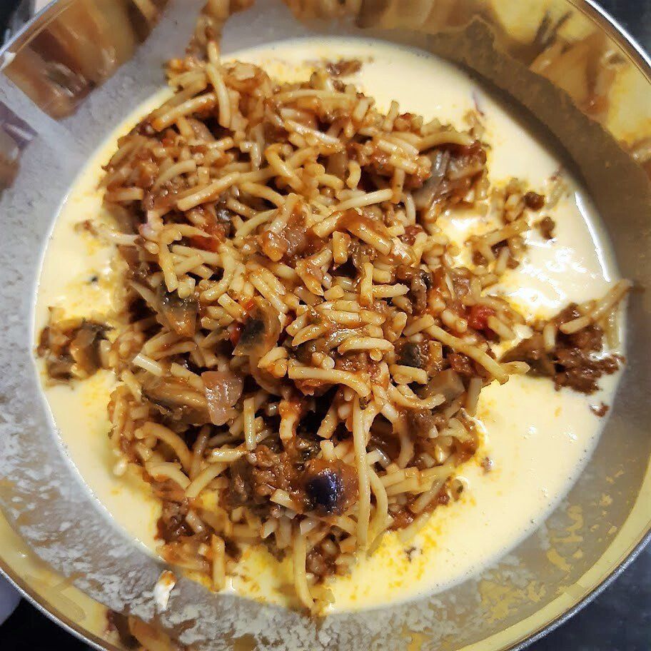 Een kom spaghetti met tomatensaus over een romige gele saus.