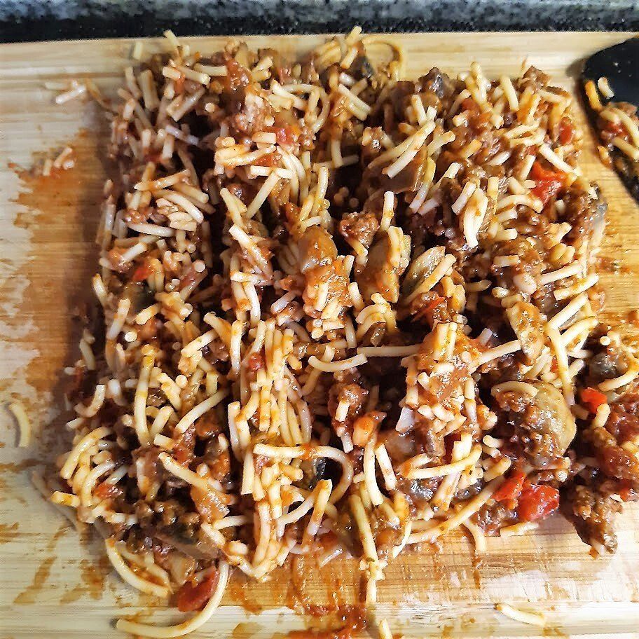 Spaghetti met vleessaus op een houten snijplank, klaar om te serveren.