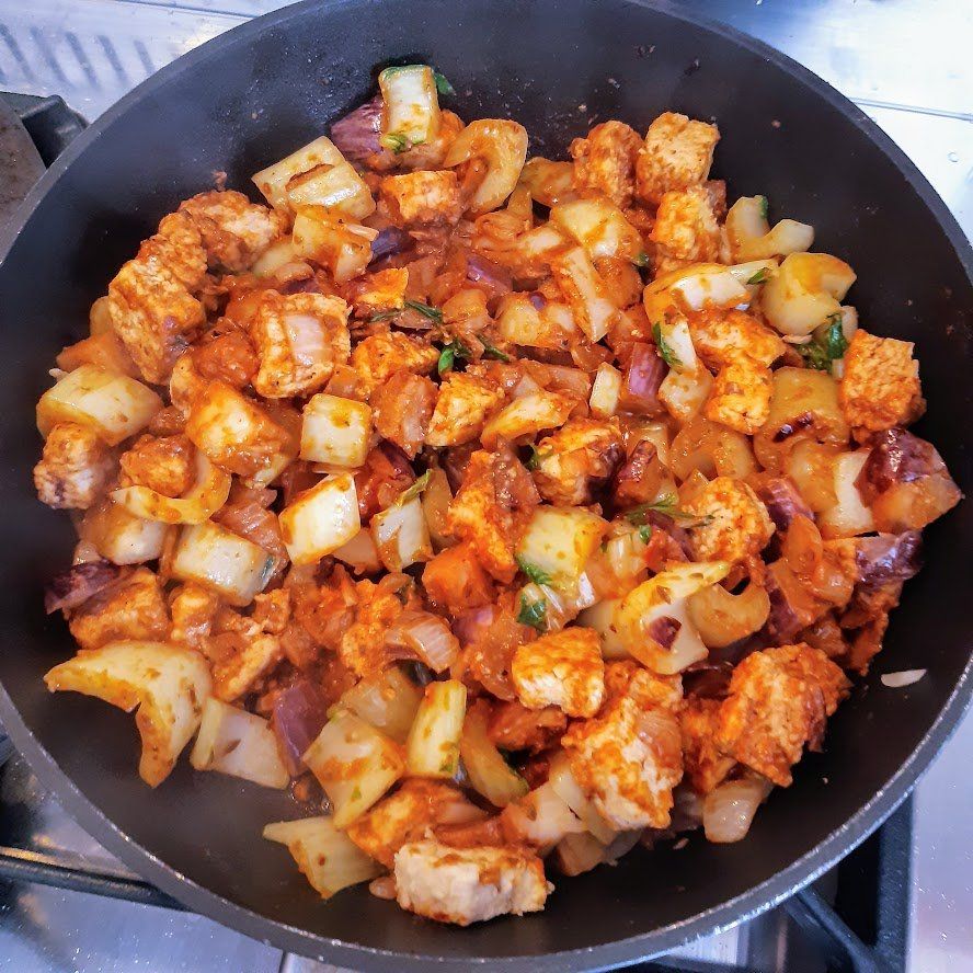 Koekenpan met een kleurrijke mix van in blokjes gesneden tofu, uien en kruiden.