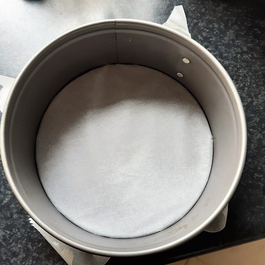 Ronde bakvorm met bakpapier op de bodem, klaar om te bakken.
