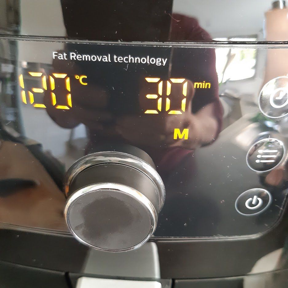 Bedieningselementen van de airfryer tonen een temperatuur van 120 °C en een tijdsduur van 30 minuten. Zwart apparaat met een bedieningsknop.
