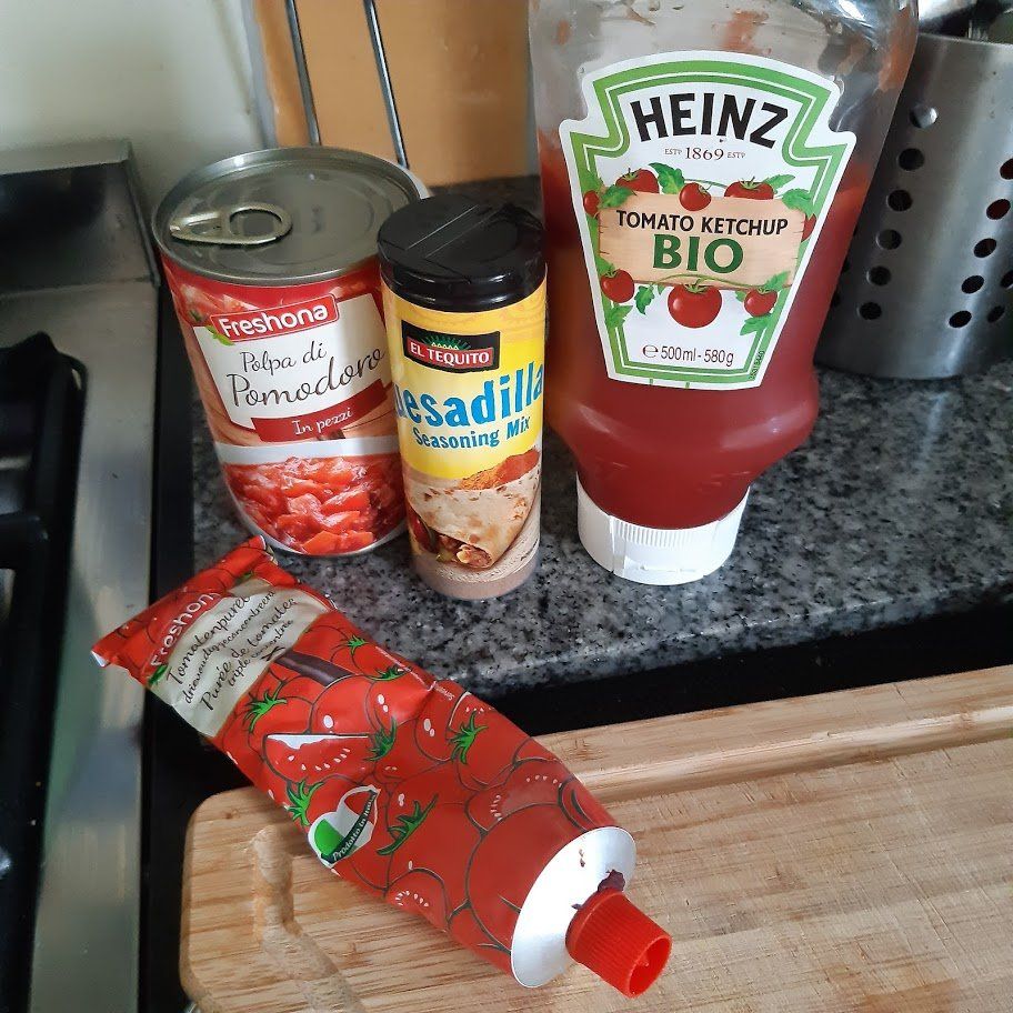 Ingrediënten voor het koken: blik geplette tomaten, kruiden, ketchup, tomatenpuree.