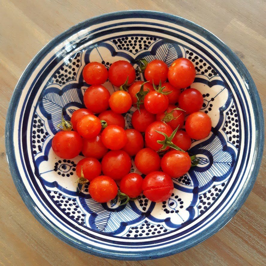 Cherrytomaatjes in een blauw-wit gestreepte schaal op een houten ondergrond.