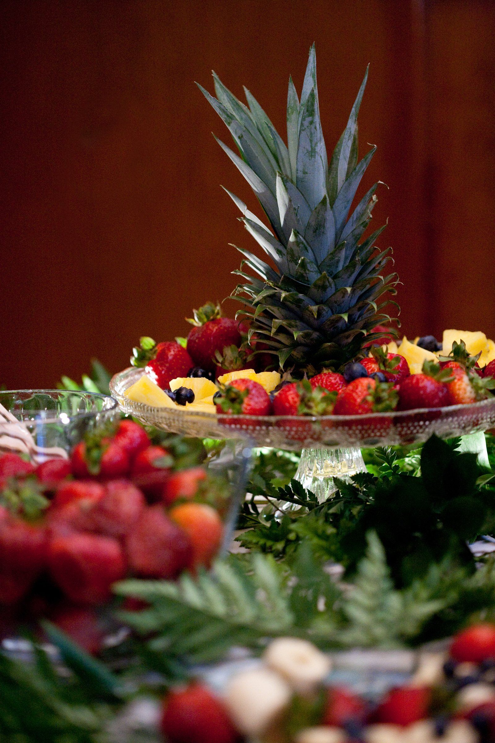 A pineapple is sitting on top of a bowl of fruit.