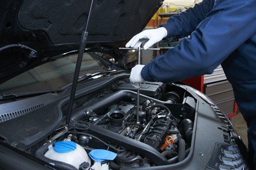 meccanico avvita le componenti di un motore esposto