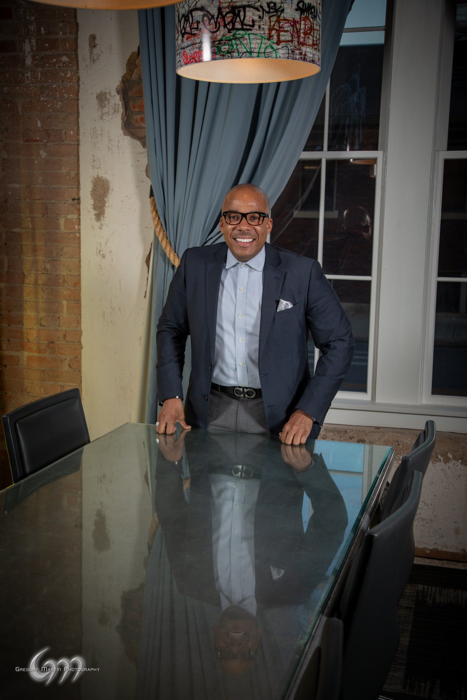 A man in a suit and tie is sitting at a conference table.