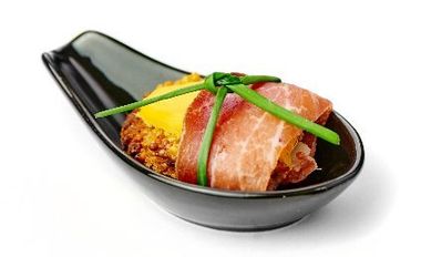 Eine schwarze Schüssel gefüllt mit Fleisch und Käse auf einem weißen Hintergrund.