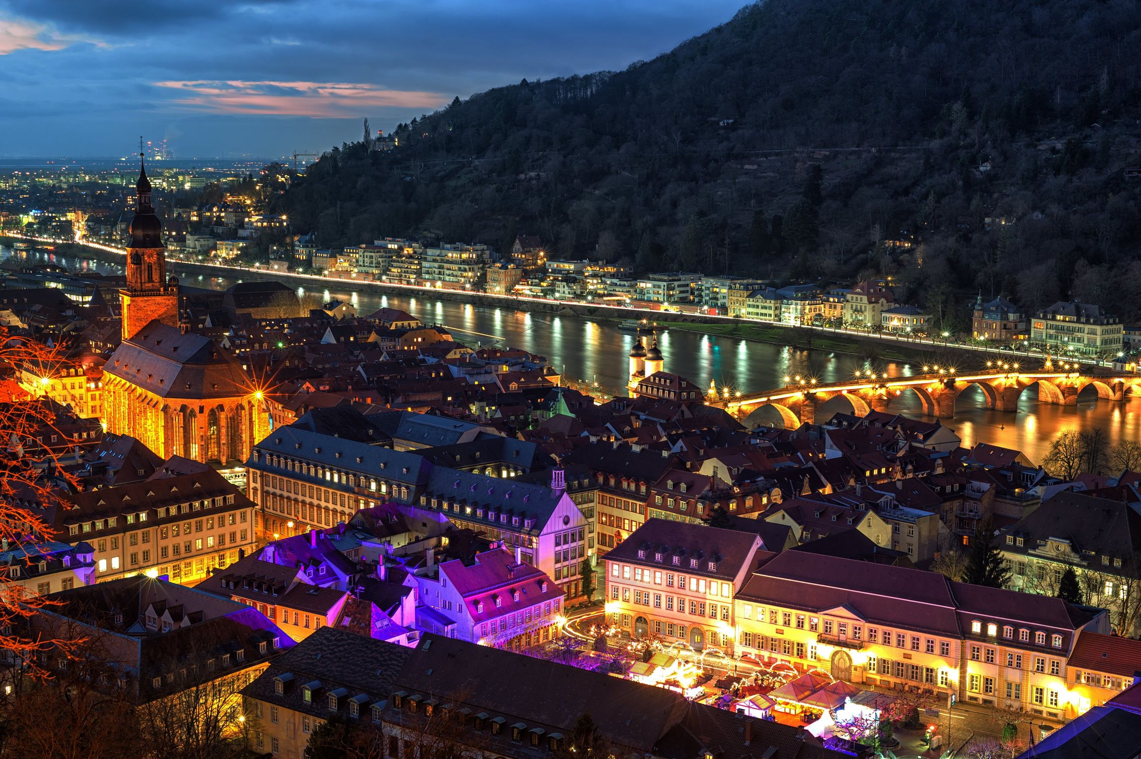 Eine Luftaufnahme einer Stadt bei Nacht mit einem Fluss im Hintergrund.
