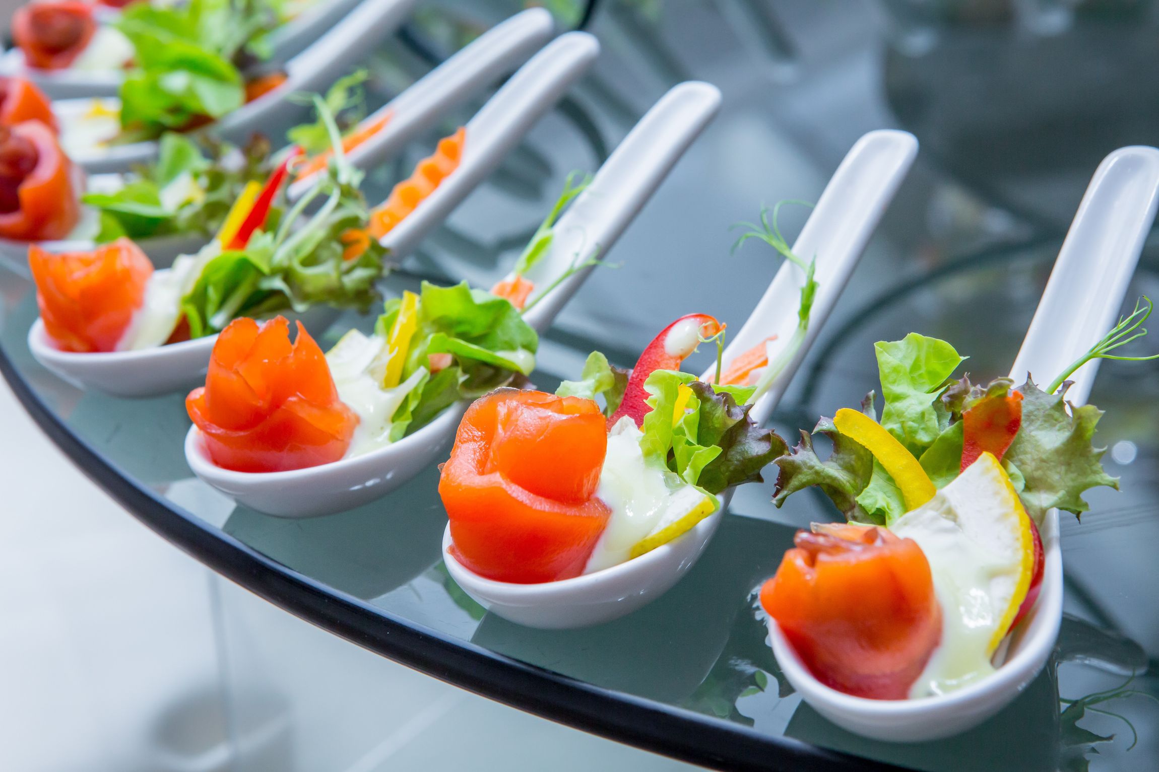 Ein Tisch, bedeckt mit Löffeln voller geräuchertem Lachs und Salat.