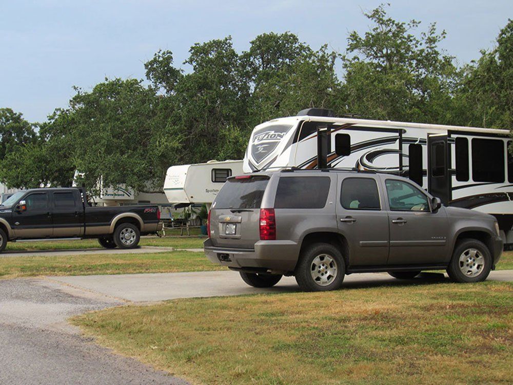 A truck and a suv are parked in a grassy area next to a rv.