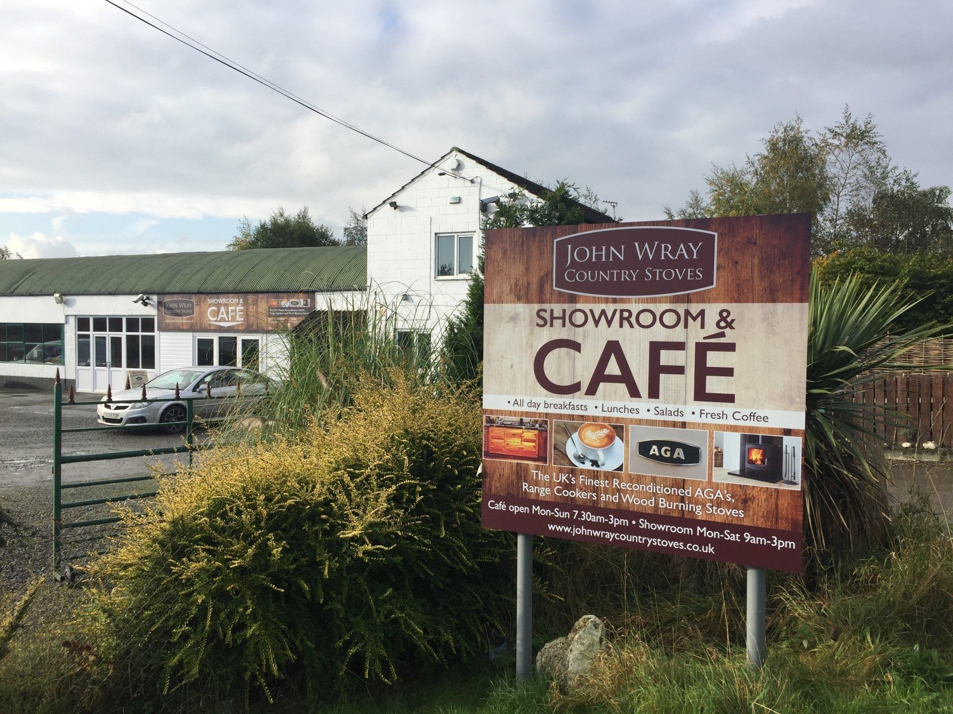 A sign for a showroom and cafe is in front of a building.